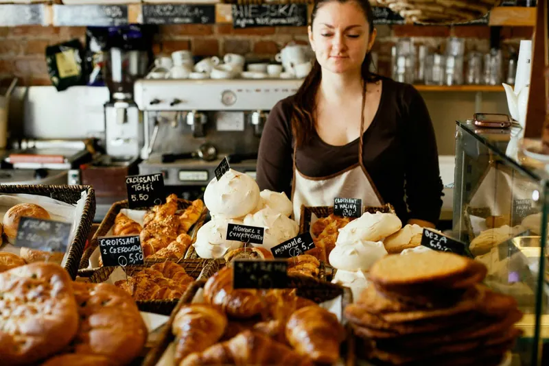 Inhaberin einer Bäckerei hinter der Theke mit Backwaren