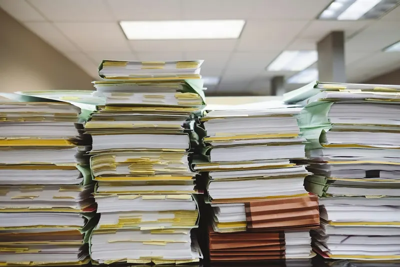 Hohe Stapel von Akten und Unterlagen in einem Büro